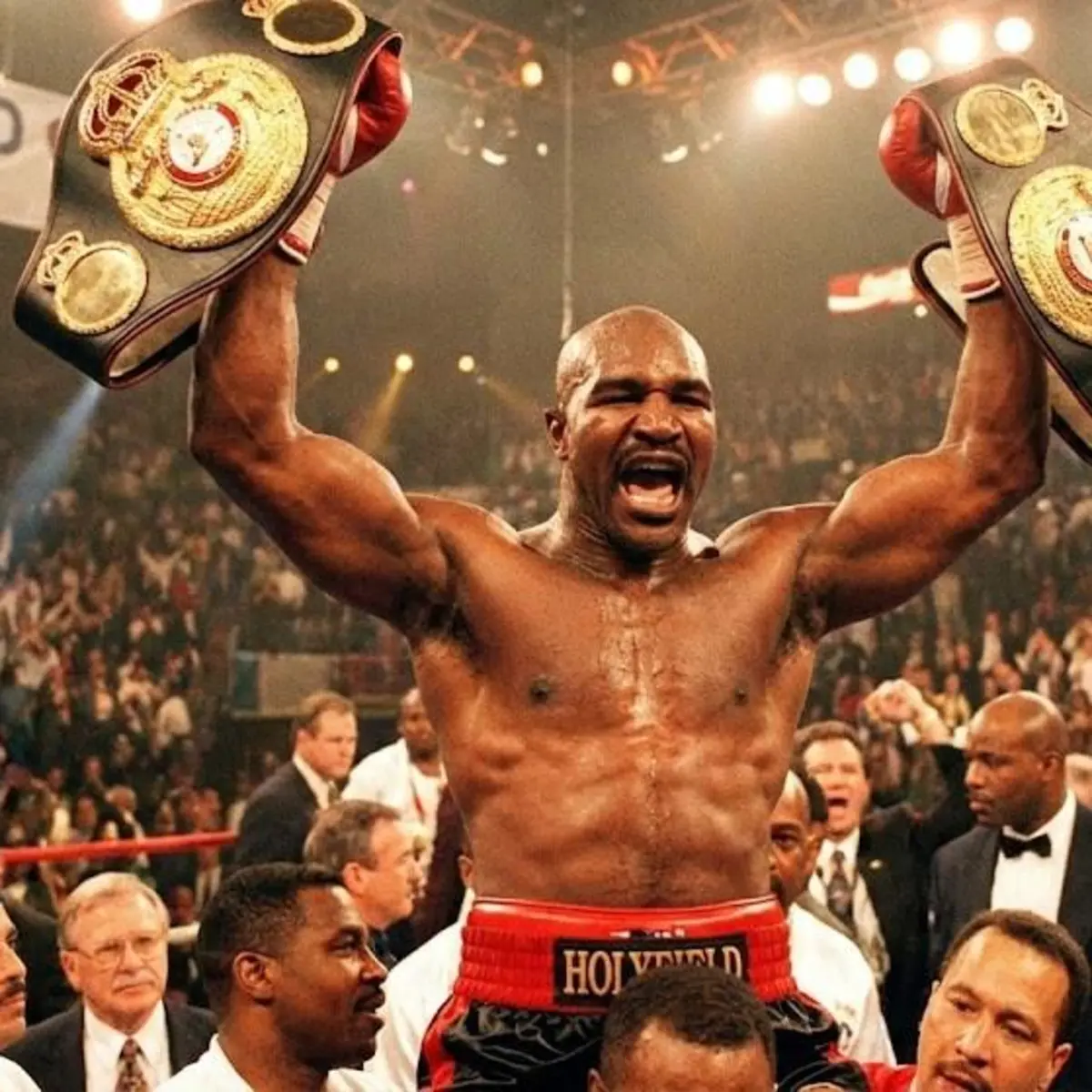 Evander Holyfield brandit ses ceintures de champion du monde poids lourds