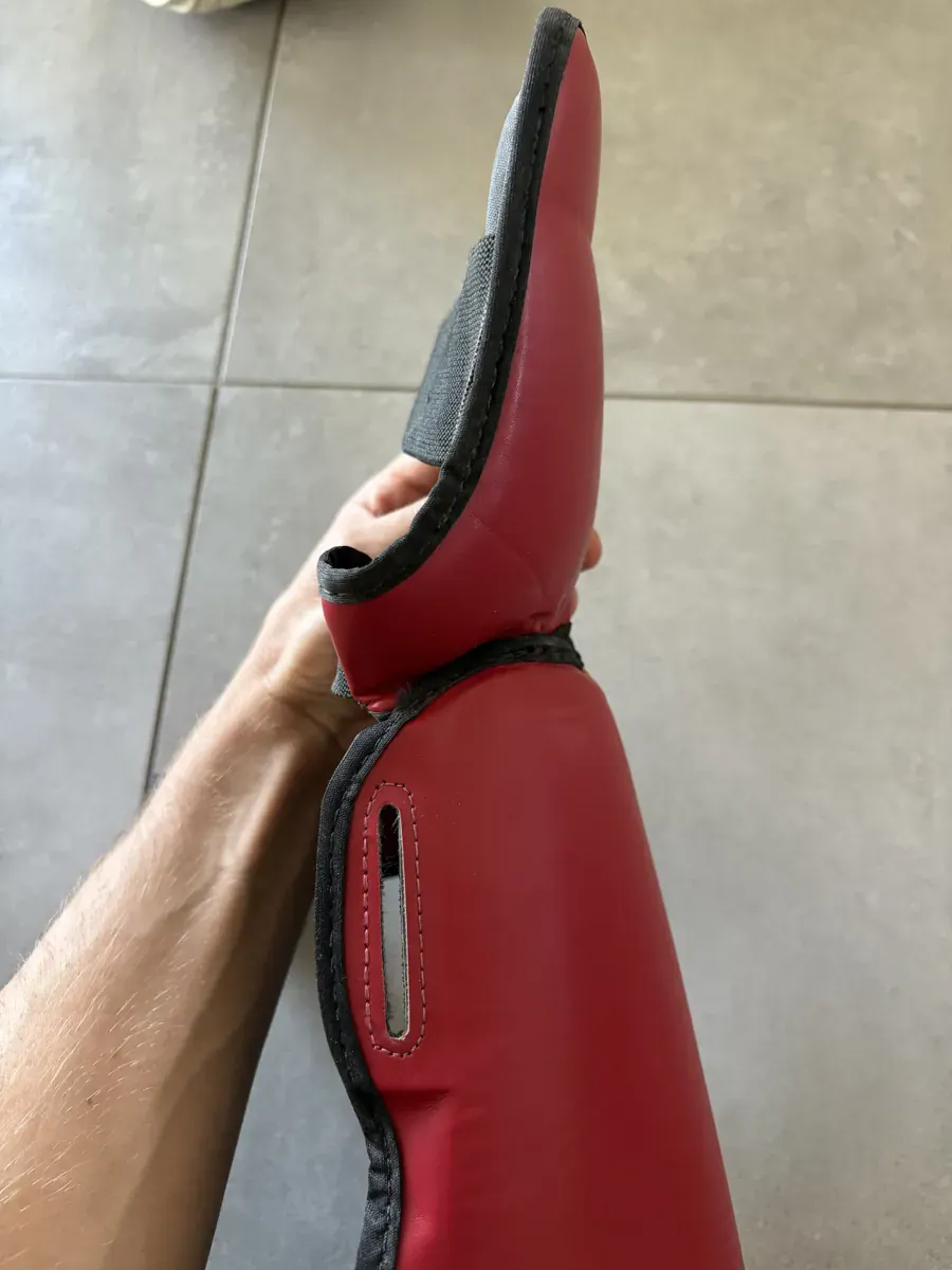 Fente de passage de sangle surpiquée sur la plaque tibiale du Fairtex SP5 rouge