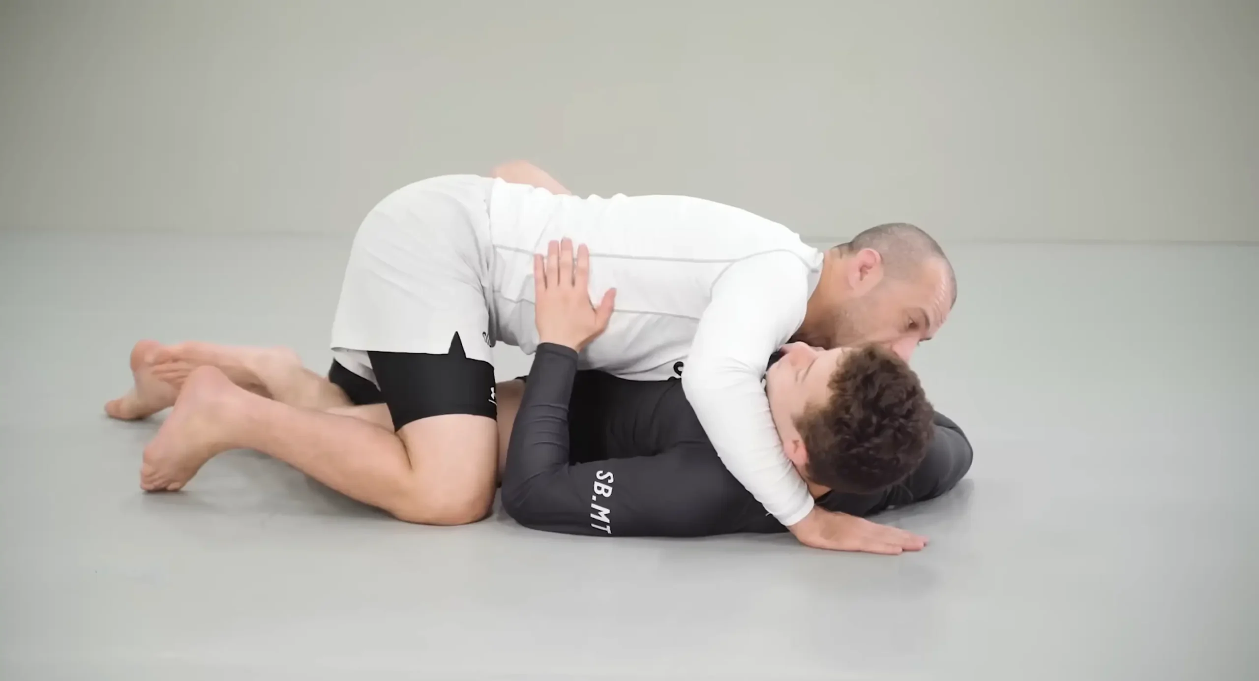 Combattant de MMA exécutant un passage de garde (guard pass) parfait en maintenant la pression