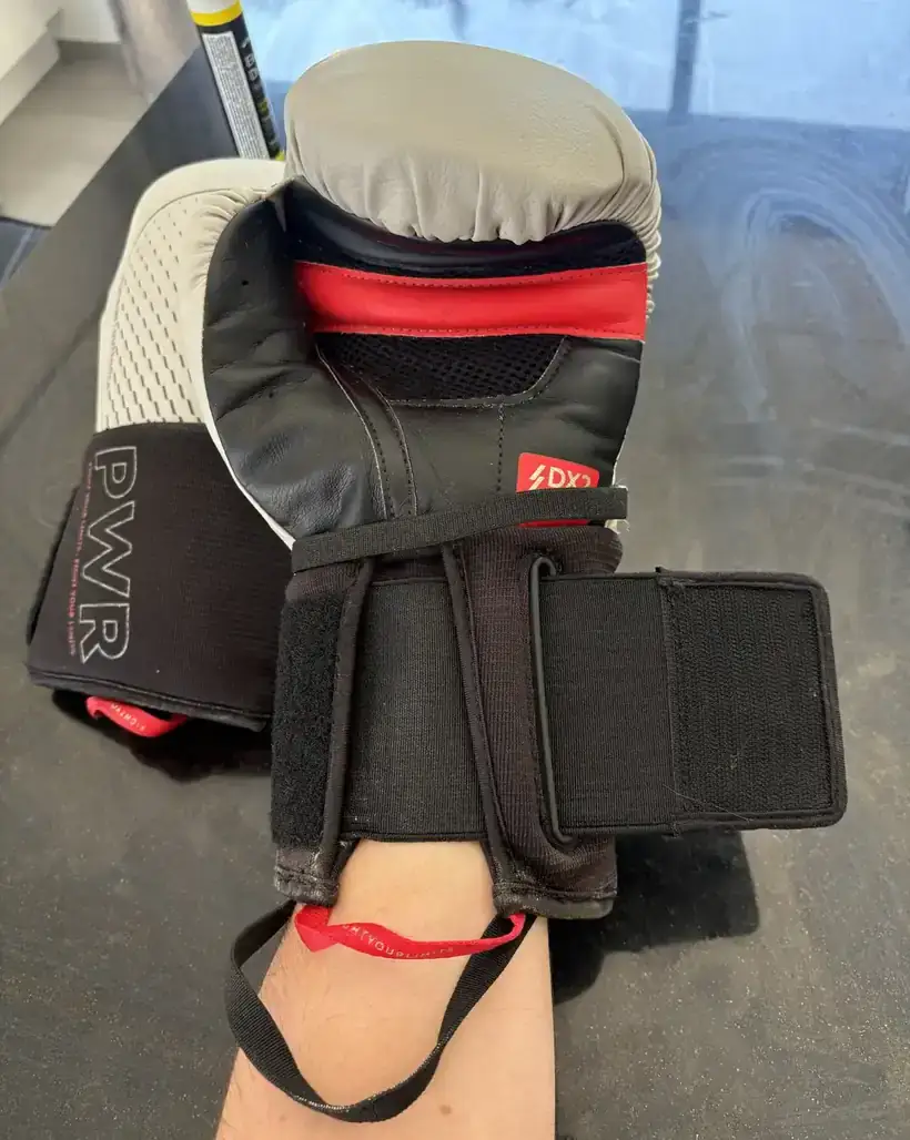 Gant de boxe Decathlon Outshock ferm&eacute; sur le poignet, sangle enroul&eacute;e, &eacute;tiquette DX2 Density et panneau de maille visibles